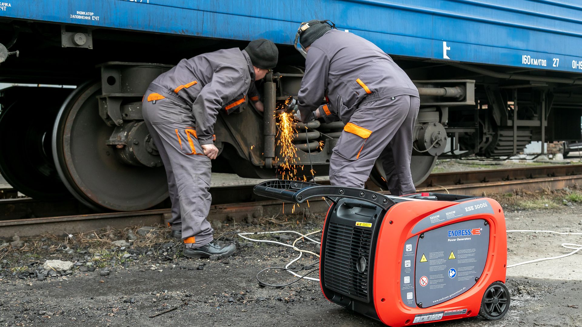 Zwei ukrainische Kollegen führen Schweißarbeiten an einem ukrainischen Zug durch. Im Vordergrund ein Generator.