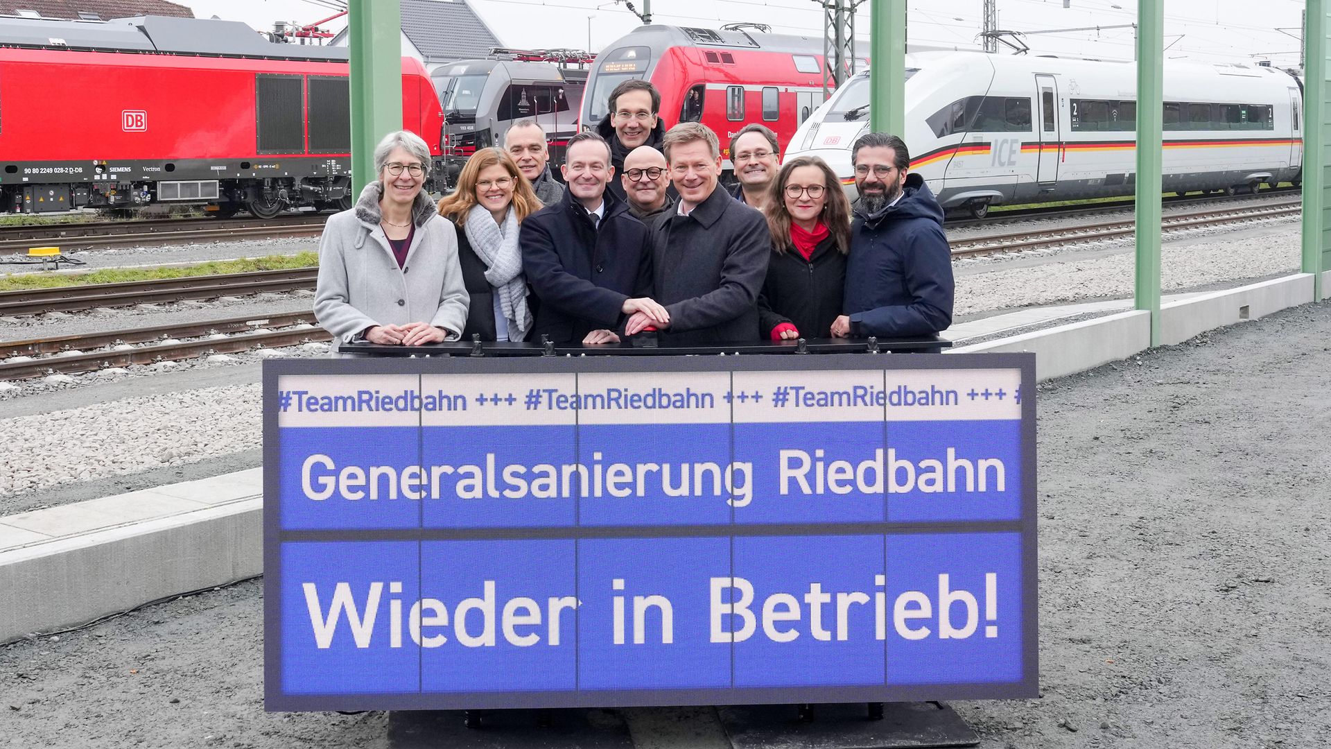 Gruppenfoto mit DB-Vorständen und Vertretern aus der Politik in Gernsheim, im Hintergrund drei Züge