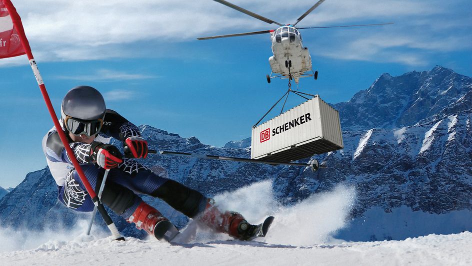 ein Skifahrer, im Hintergrund ein Hubschrauber, der einen DB Schenker-Container hebt